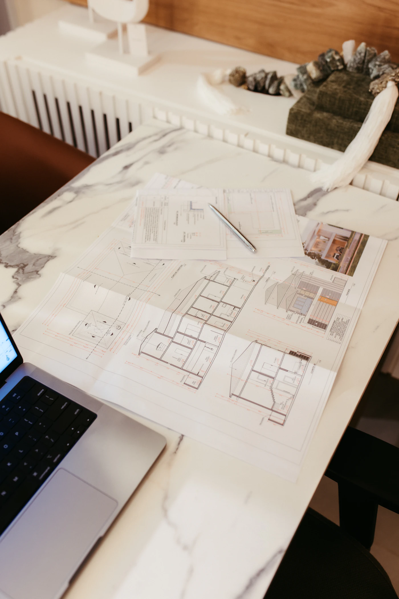 Planos técnicos y un ordenador sobre una mesa de trabajo